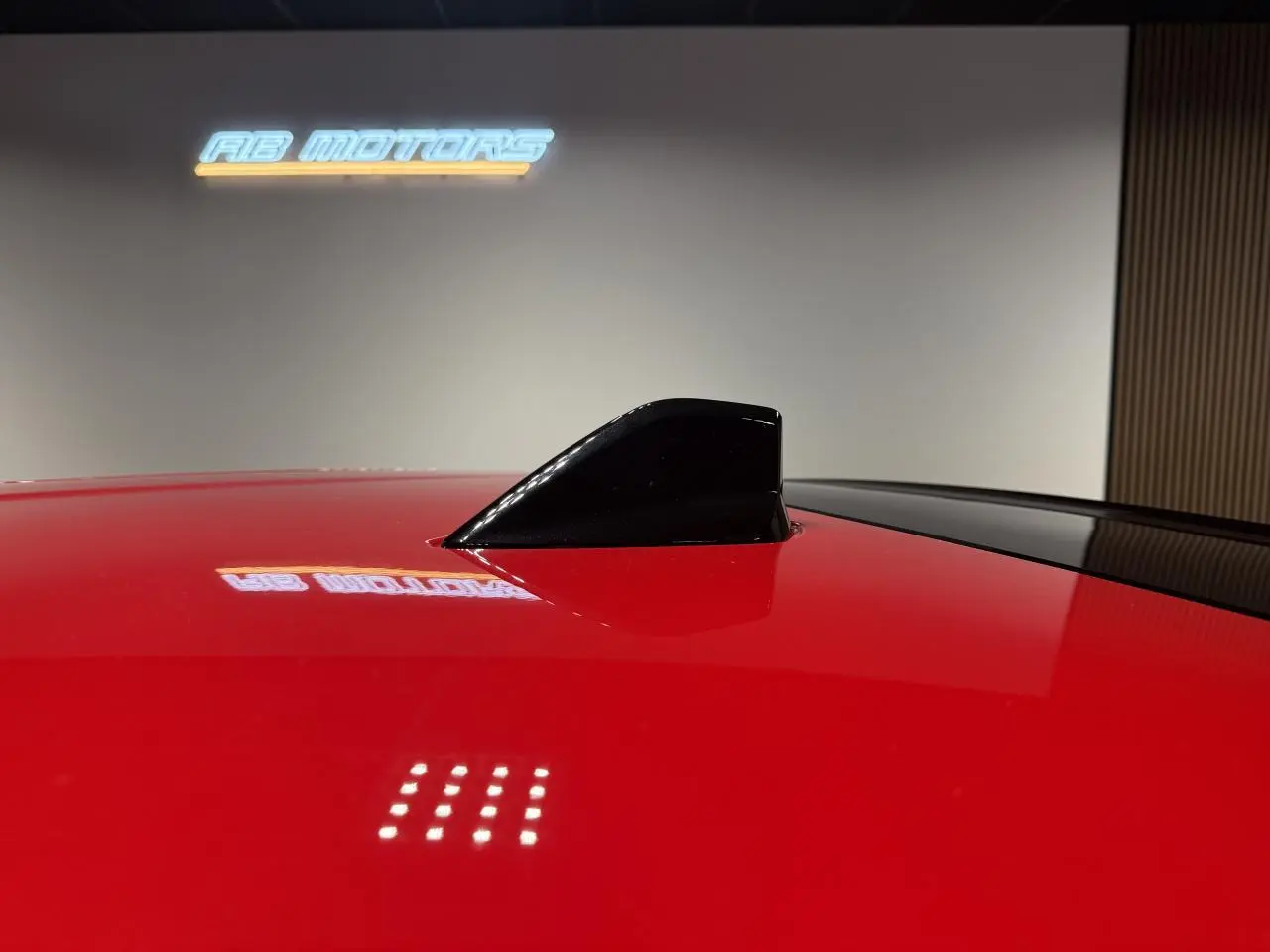 Gros plan sur l'antenne requin noire brillante sur le toit rouge foncé de la FIAT 600 Hybrid 2025.