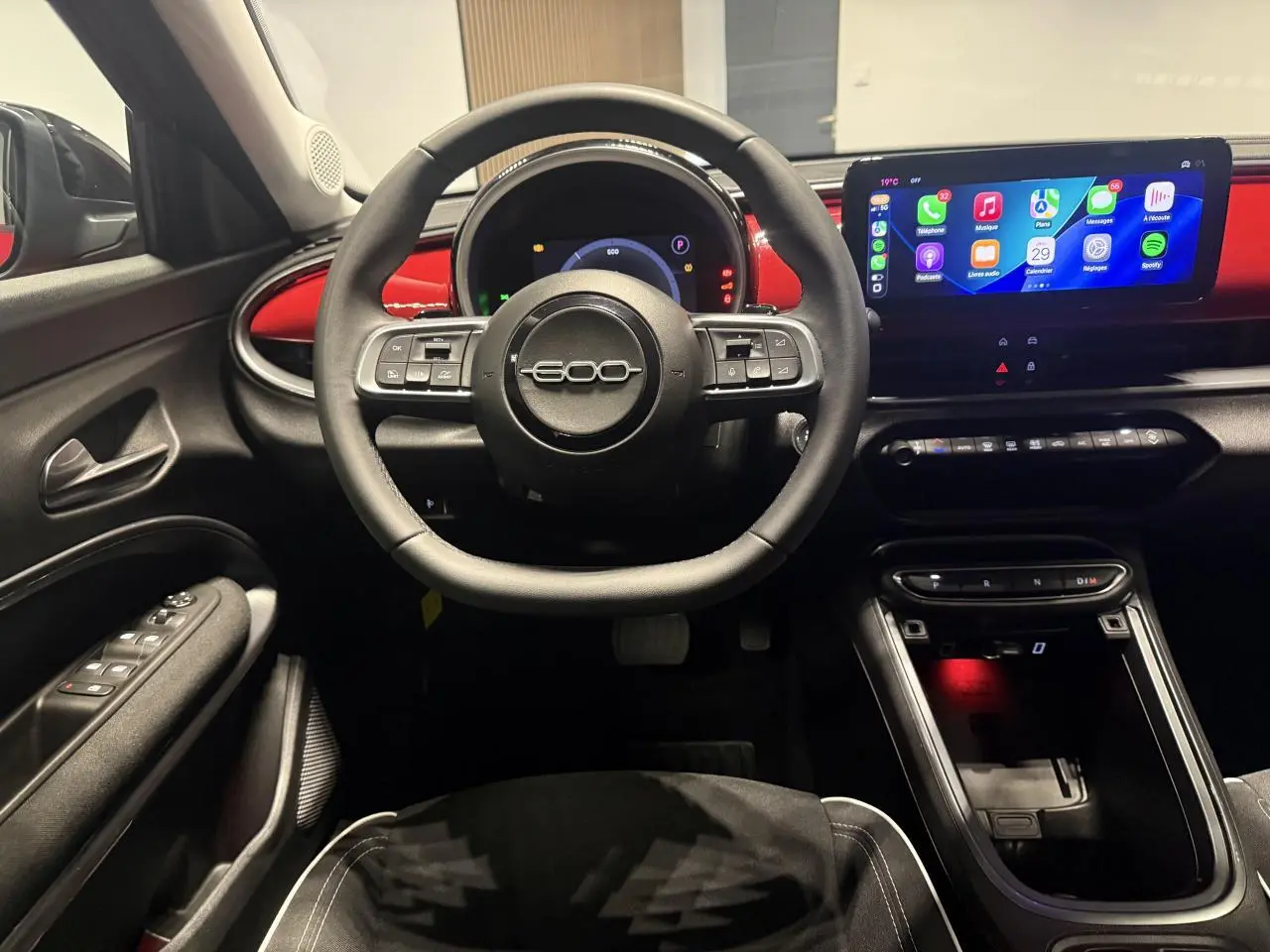 Vue intérieure frontale du poste de conduite du Fiat 600 rouge foncé avec volant multifonction et écran tactile large.