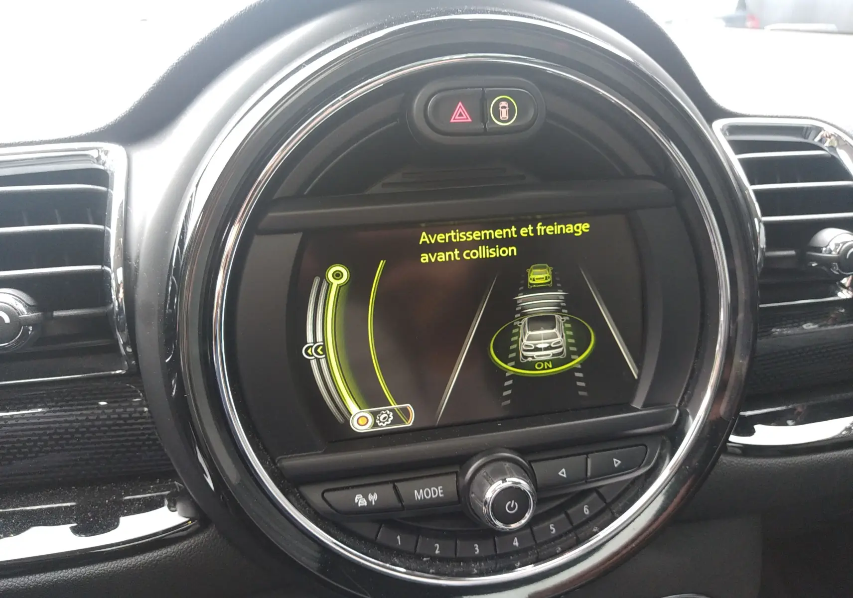 Écran central rond du tableau de bord MINI Clubman 2017 affichant l'alerte de freinage avant collision.