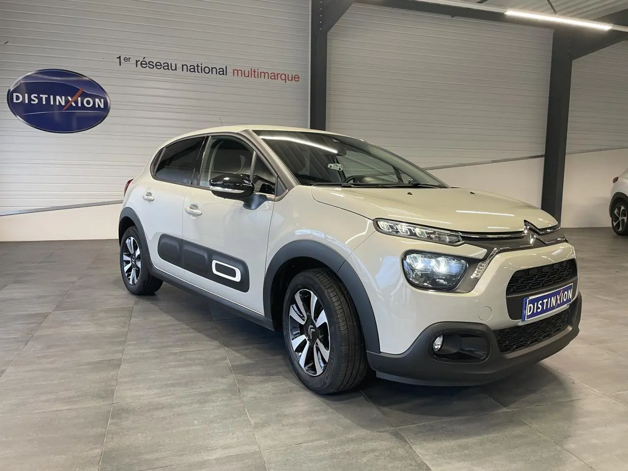 Citroën C3 beige clair vue 3/4 avant droit avec Airbump noir et jantes alliage diamantées en showroom.
