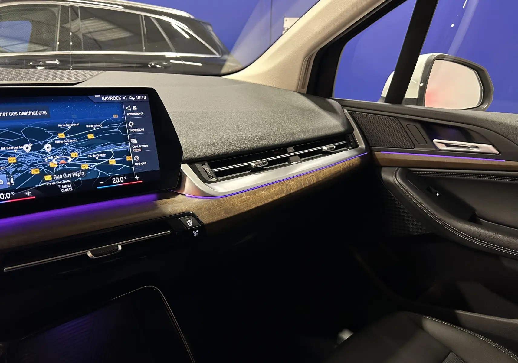 Vue intérieure côté passager de la BMW Série 2 Active Tourer 218i 2022, avec tableau de bord bois et éclairage d’ambiance violet.