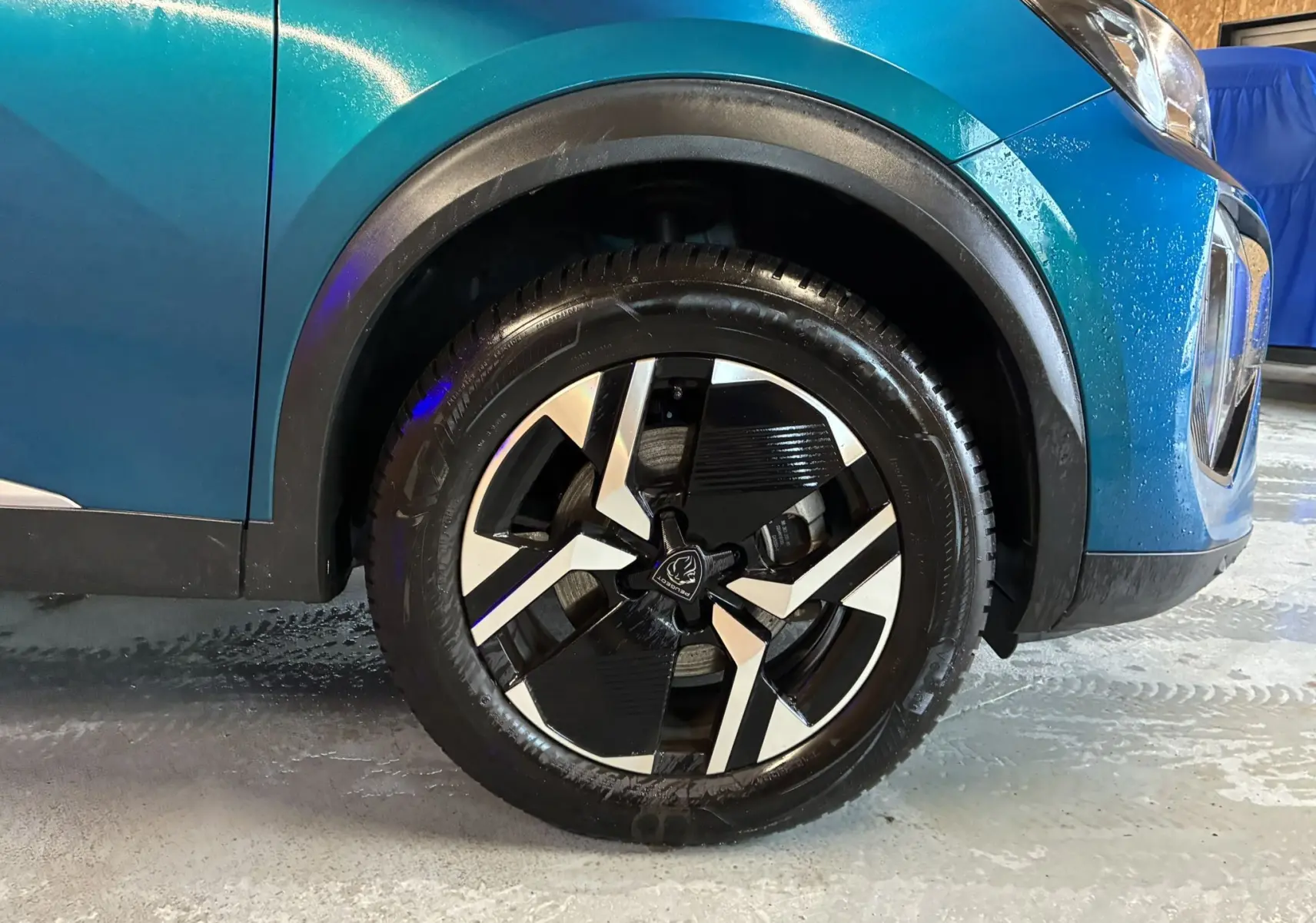 Gros plan sur la roue avant droite d’un Peugeot 2008 bleu 2025, mettant en valeur la jante noire et argentée au design moderne.