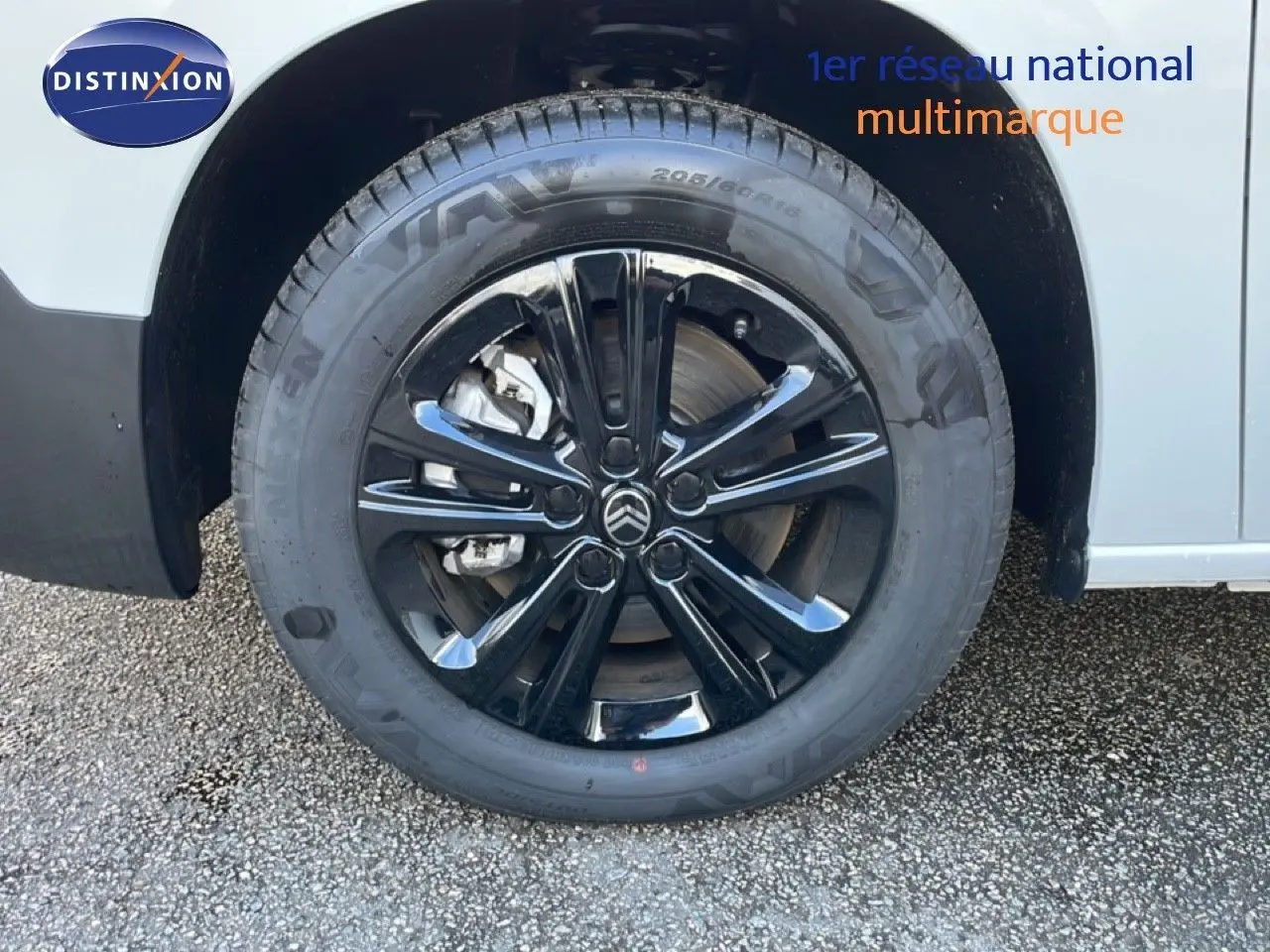 Gros plan sur la roue avant gauche d’un Citroën Berlingo blanc glacier avec jante noire brillante.