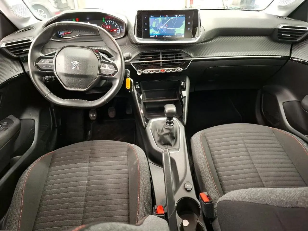 Vue intérieure avant de la Peugeot 208 2020, tableau de bord avec volant compact cuir et écran tactile central.