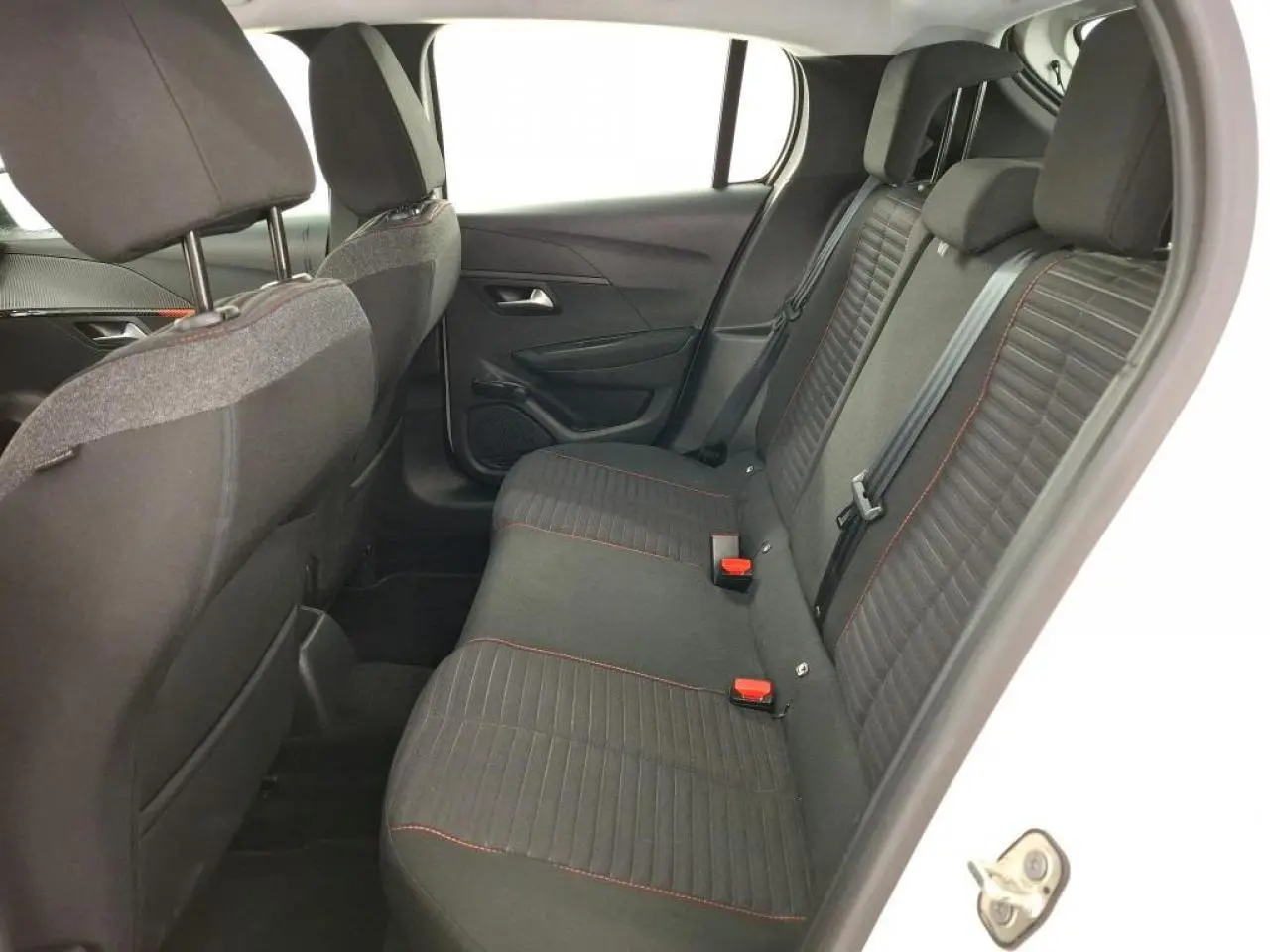 Vue intérieure côté droit sur la banquette arrière noire avec surpiqûres orange de la Peugeot 208 blanche de 2020.
