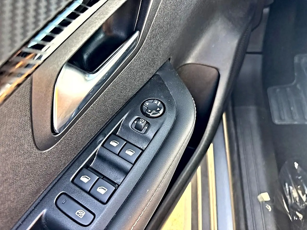 Gros plan sur la commande des vitres électriques et rétroviseurs côté conducteur de la Peugeot 208 gris artense.