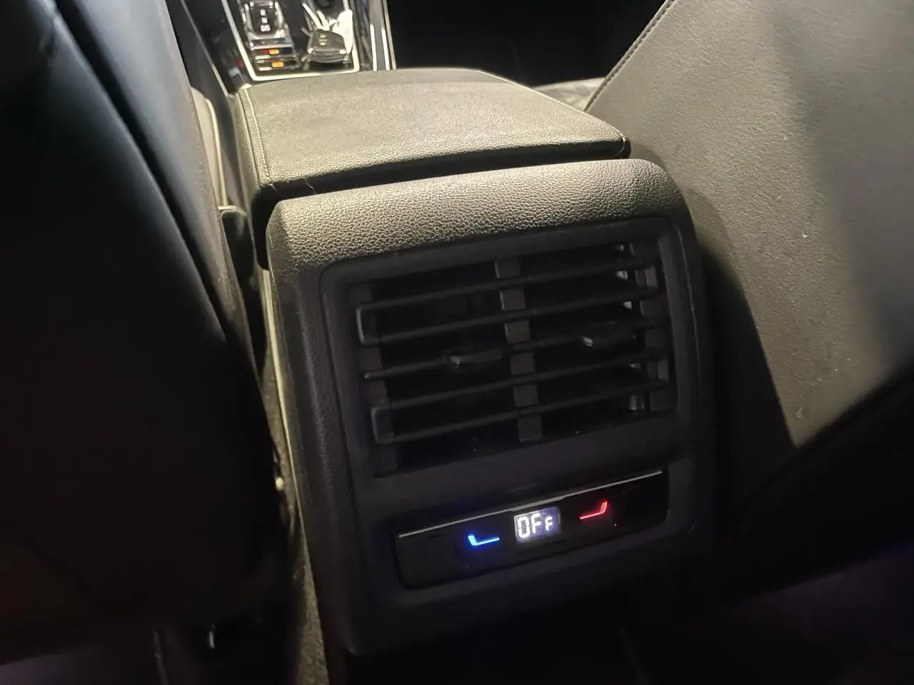 Détail de la console centrale arrière noire avec diffuseur d'air et commandes de siège chauffant éteintes sur Volkswagen Golf VIII R-Line.