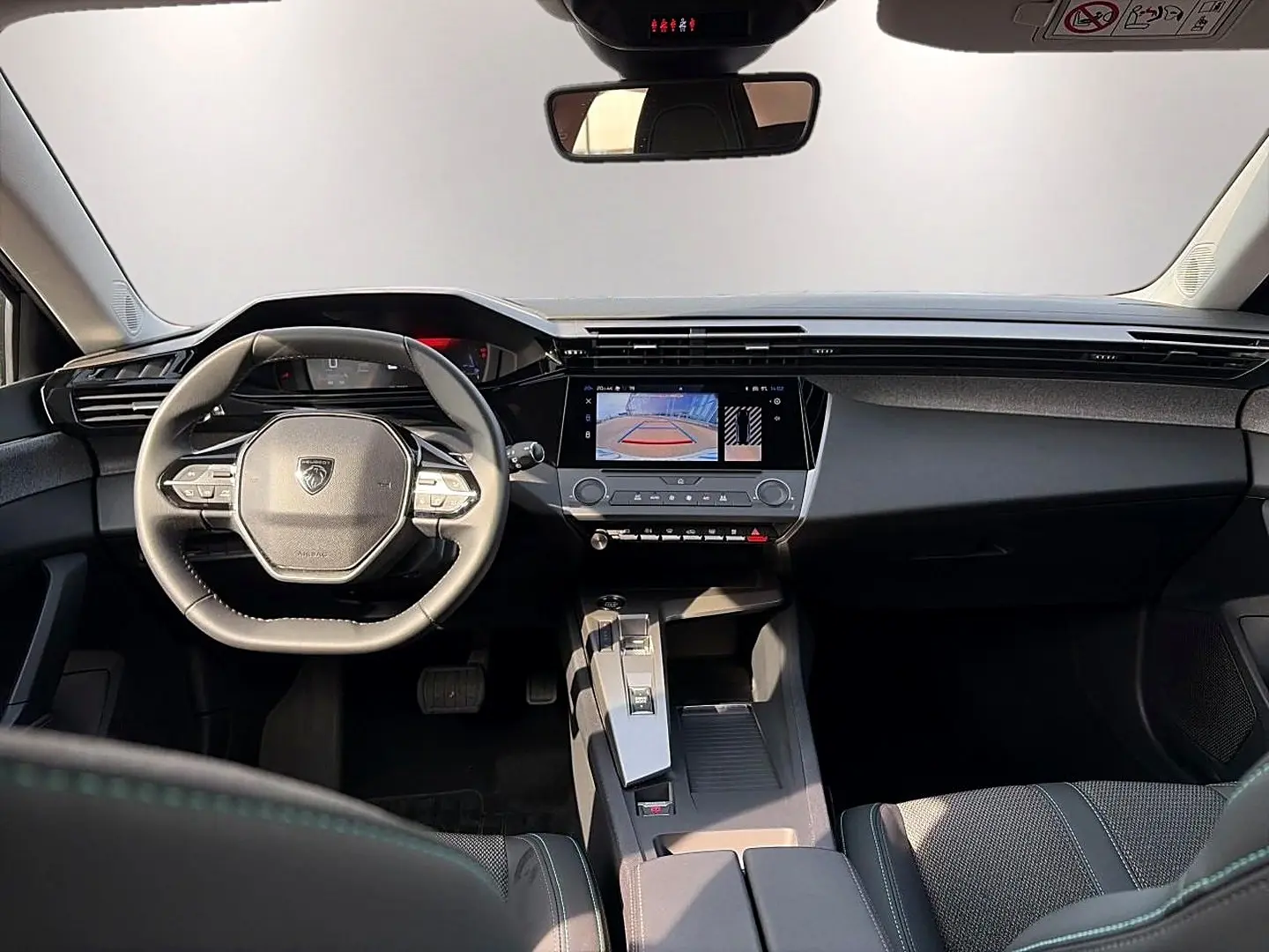 Vue intérieure avant de la Peugeot 308 noire 2025, avec volant multifonction et écran tactile affichant la caméra de recul.
