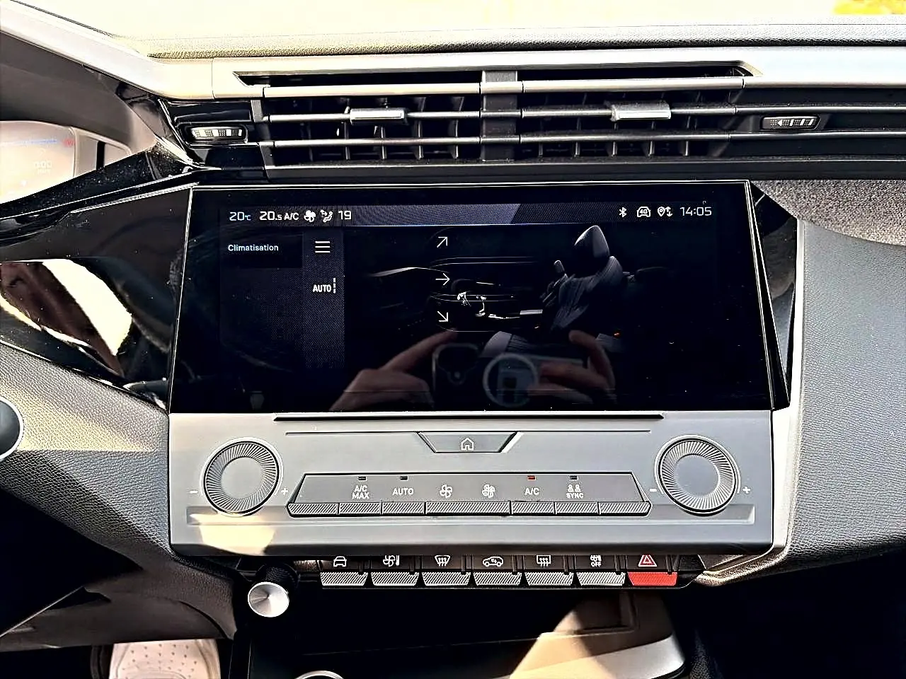 Vue rapprochée de la console centrale de la Peugeot 308 2025, écran tactile et commandes climatisation en noir et gris.