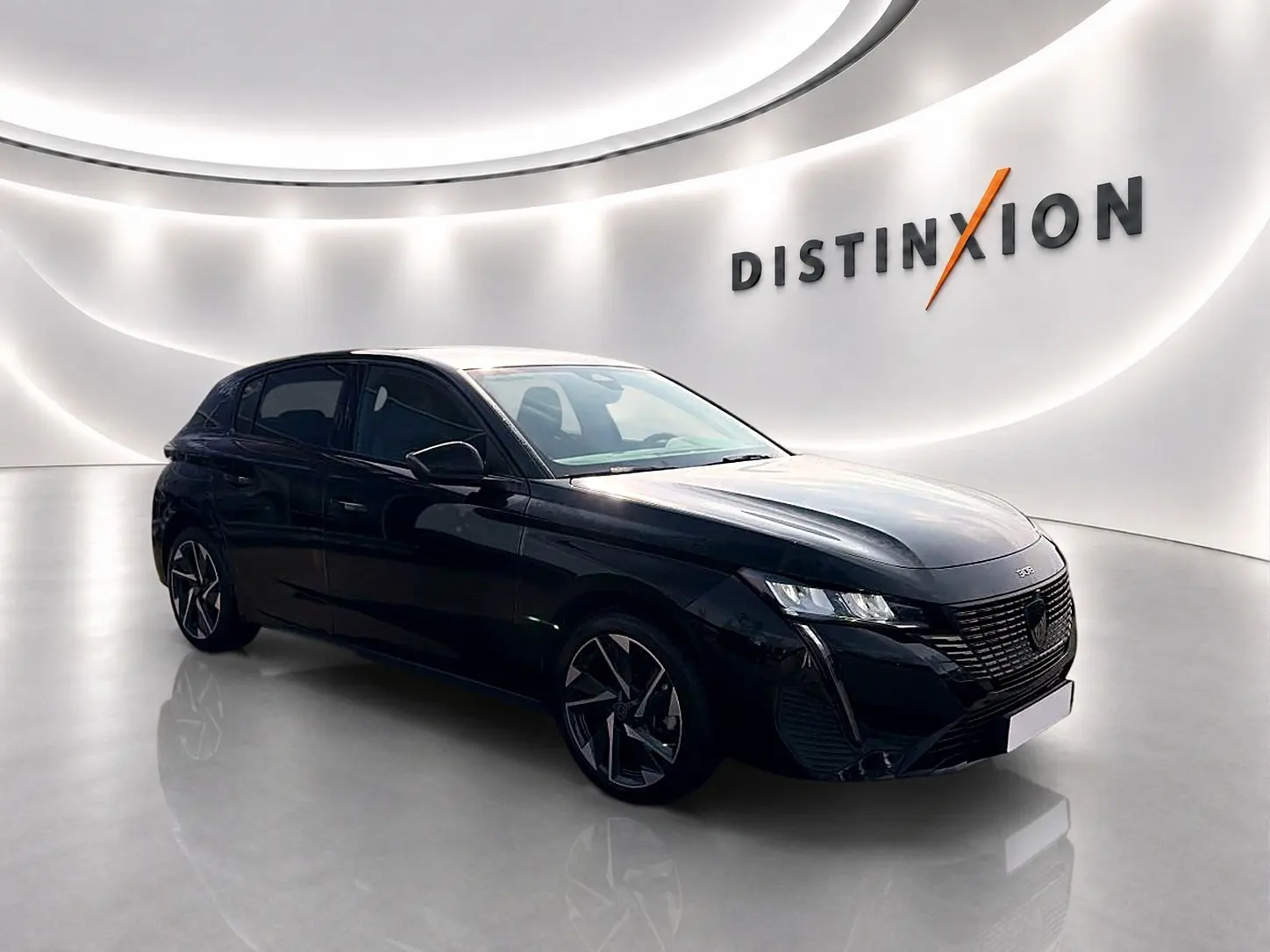 Peugeot 308 noire vue en 3/4 avant droit dans un showroom lumineux avec jantes alu distinctives.