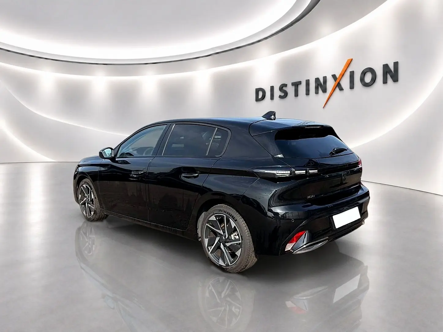 Peugeot 308 noire vue 3/4 arrière droit dans un showroom lumineux avec jantes alliage et vitres surteintées.