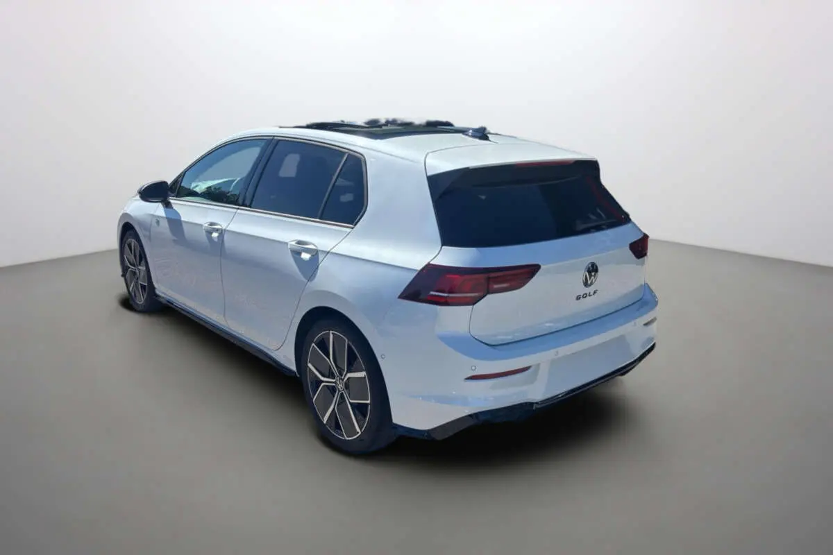 Vue 3/4 arrière droite d'une Volkswagen Golf blanche oryx avec vitres surteintées et jantes alu 18 pouces.