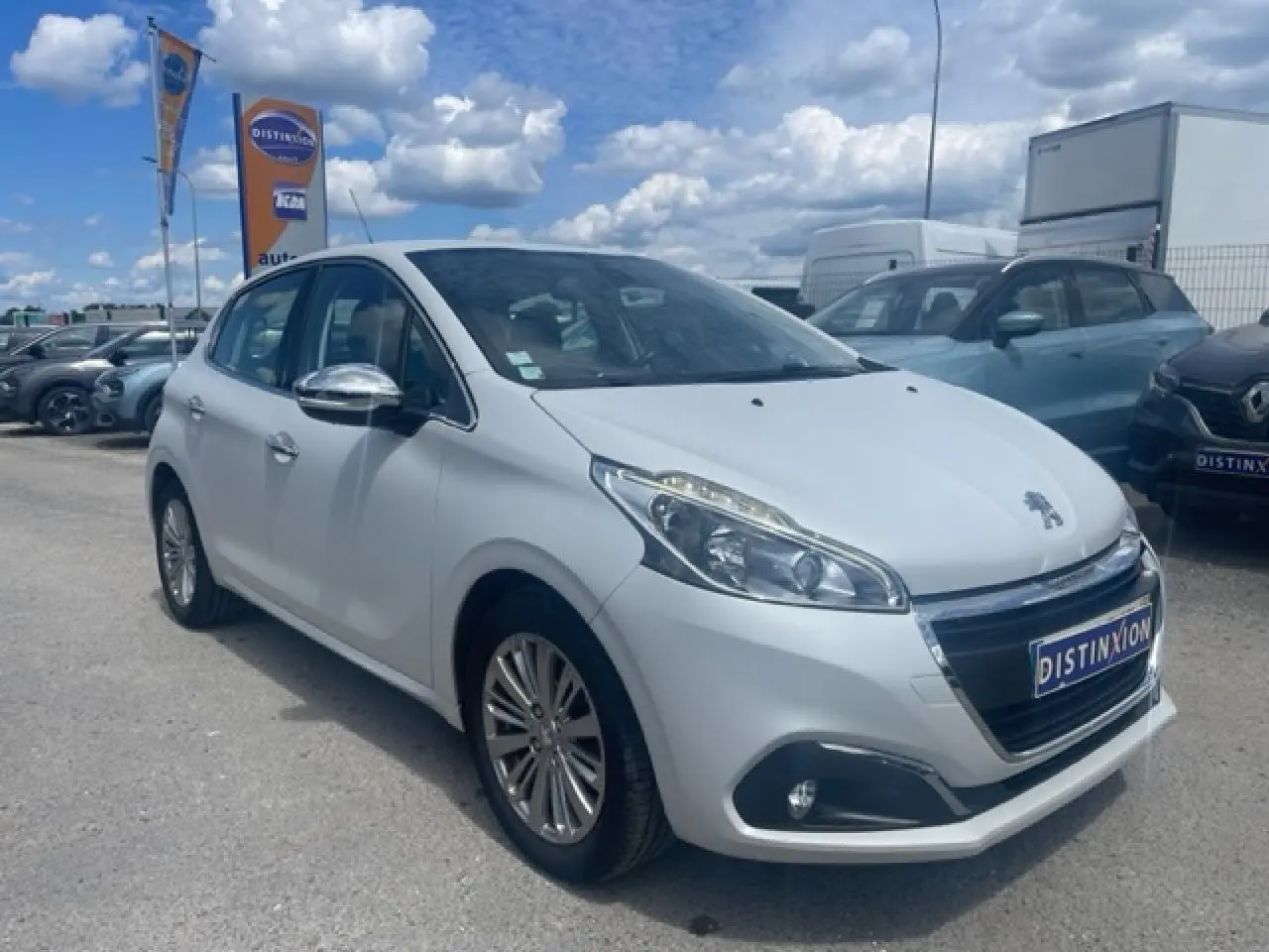 Peugeot 208 blanc perle vue 3/4 avant droit avec jantes alliage et rétroviseurs chromés, stationnée en extérieur.