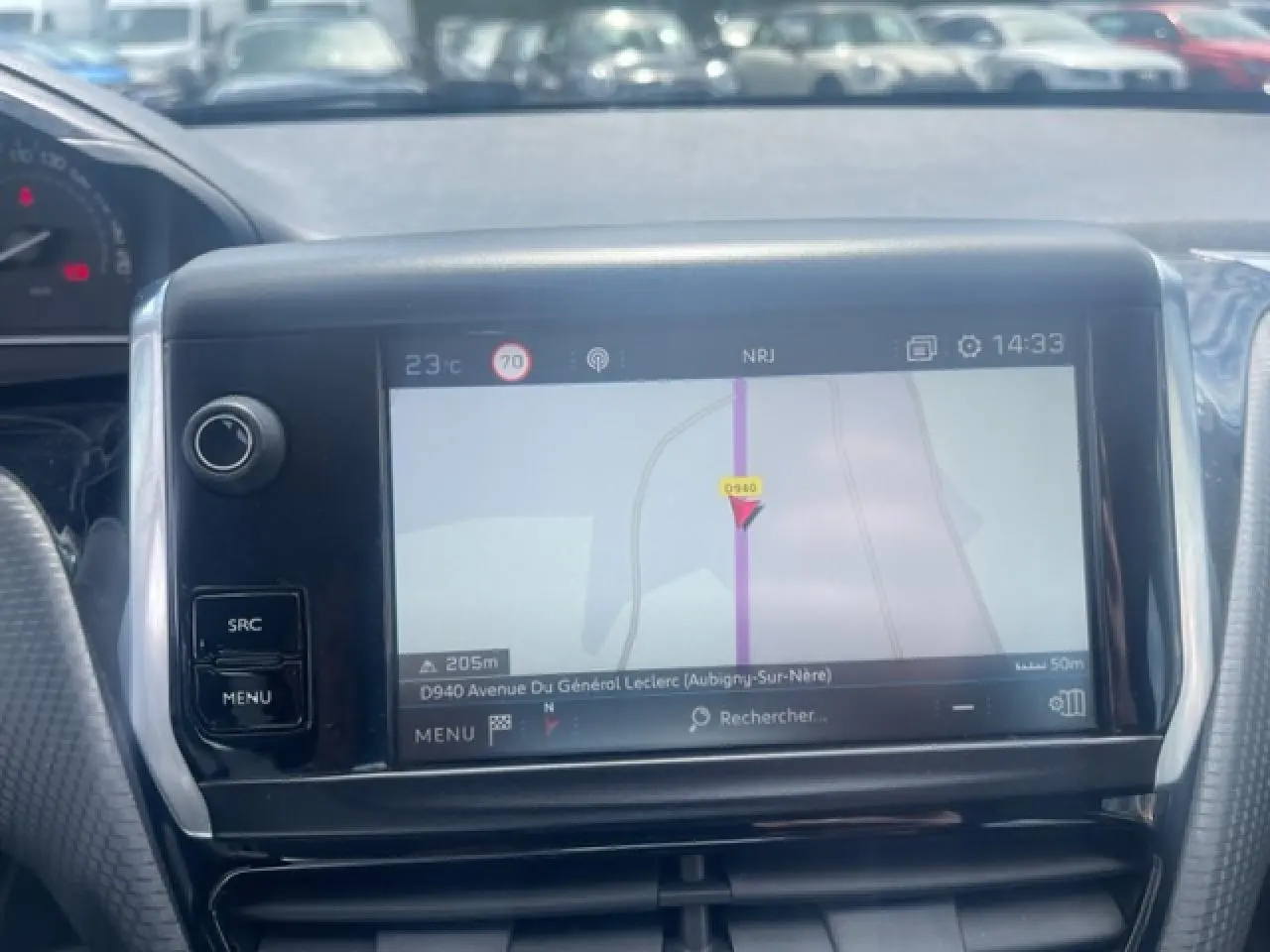 Vue rapprochée de l’écran tactile de navigation 3D de la Peugeot 208 blanche perle, avec commandes latérales visibles.