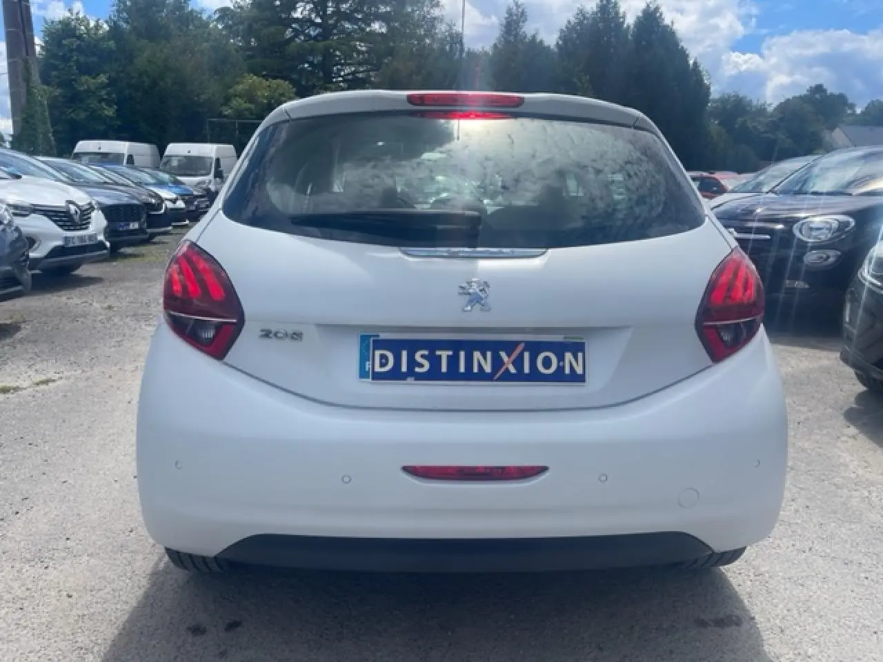 Vue arrière d'une Peugeot 208 blanche perle avec feux arrière rouges et plaque d'immatriculation Distinxion.