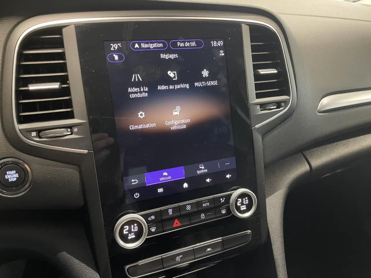 Vue rapprochée de la console centrale tactile verticale de la Renault Mégane 2023 avec commandes climatisation et démarrage.