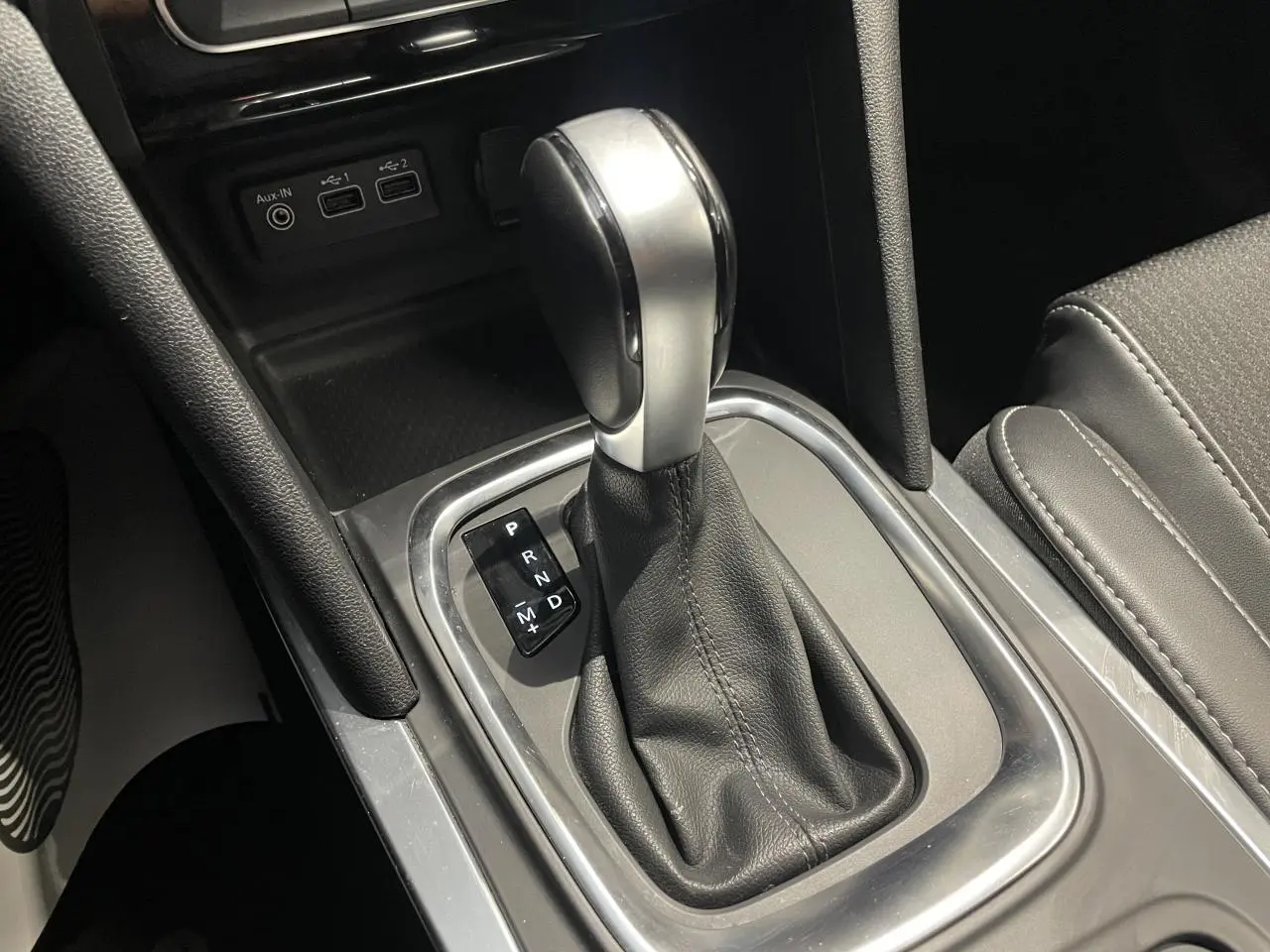 Gros plan sur la console centrale de la Renault Mégane 2023, levier de vitesse automatique et prises USB visibles.