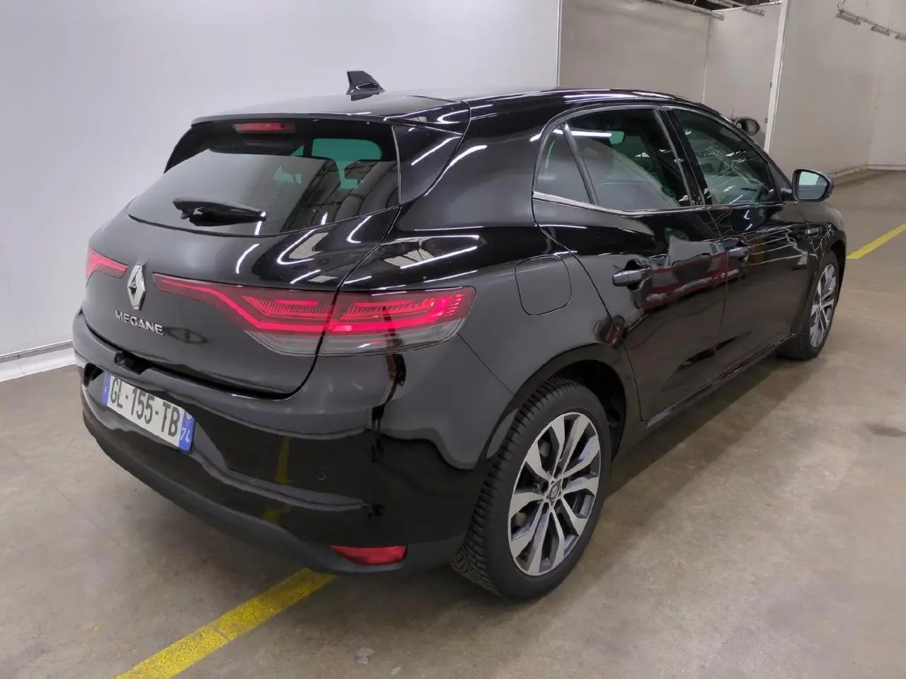 Renault Mégane noire métal vue 3/4 arrière droit, avec feux arrière LED et jantes alliage 17 pouces.