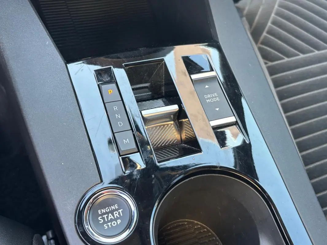 Gros plan sur la console centrale noire brillante de la Lancia Ypsilon hybride avec boutons de boîte auto et démarrage start/stop.