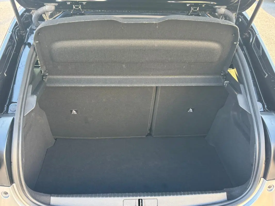 Vue plongeante sur le coffre ouvert d'une Lancia Ypsilon gris 2025, montrant un espace de rangement propre et vide.