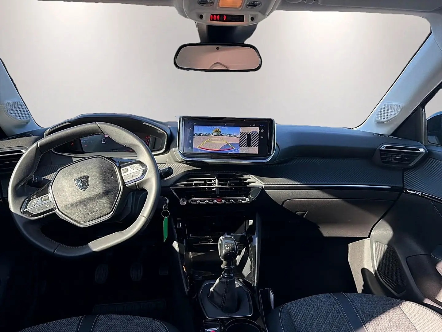 Vue intérieure avant de la Peugeot 208 1.2 100 Allure 2025, volant multifonction, écran tactile et levier de vitesse manuel.