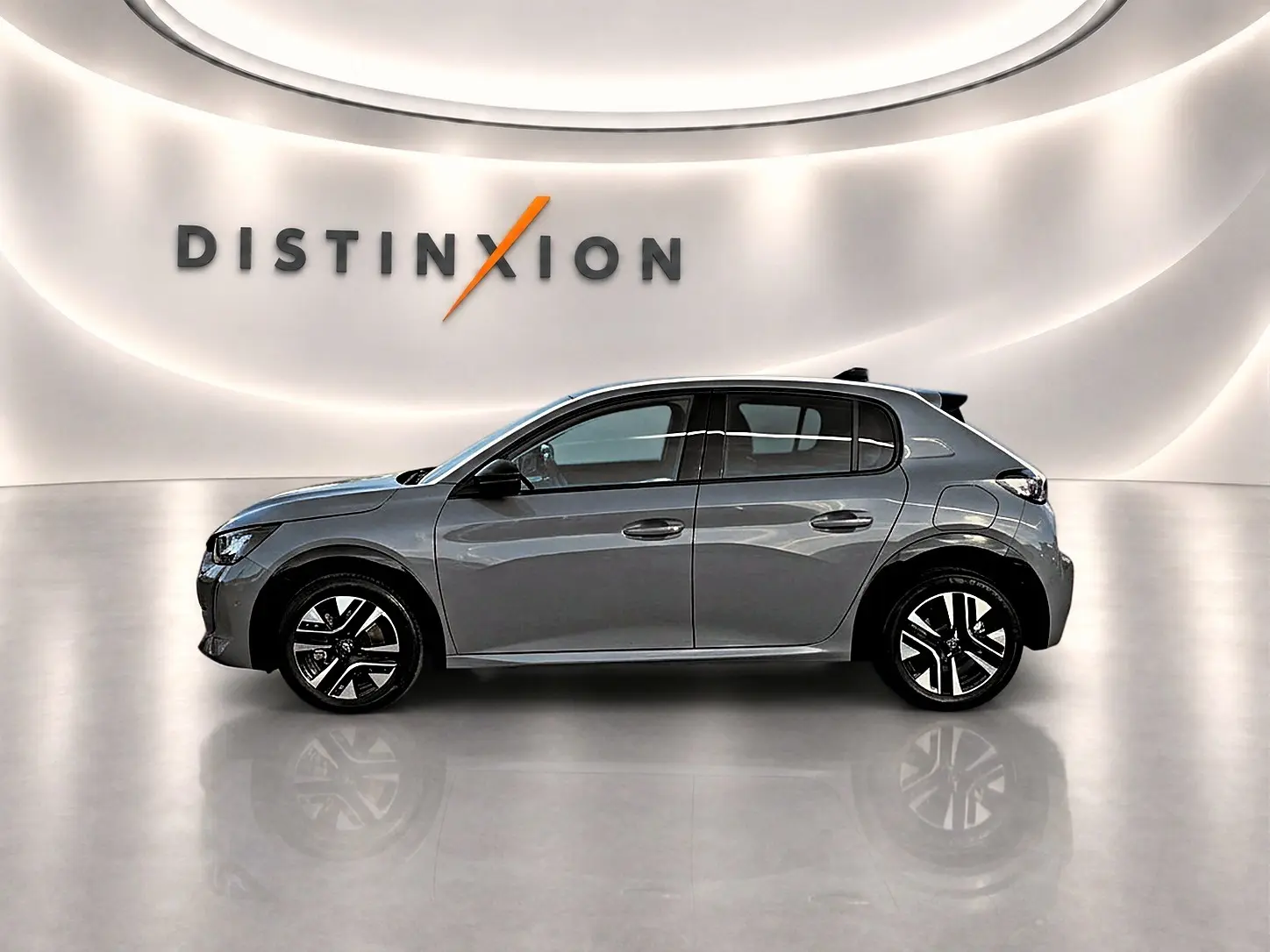 Profil droit d'une Peugeot 208 1.2 100 Allure gris selenium dans un showroom lumineux avec logo Distinxion en arrière-plan.