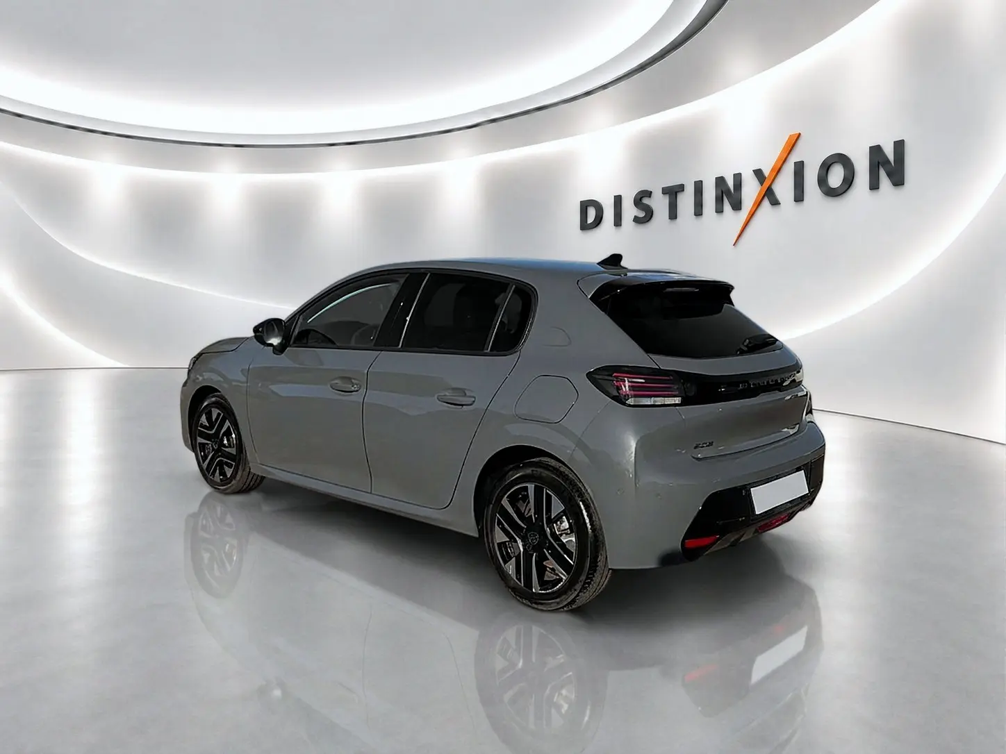 Peugeot 208 gris selenium vue 3/4 arrière droit en intérieur avec jantes alliage noires et vitres teintées.