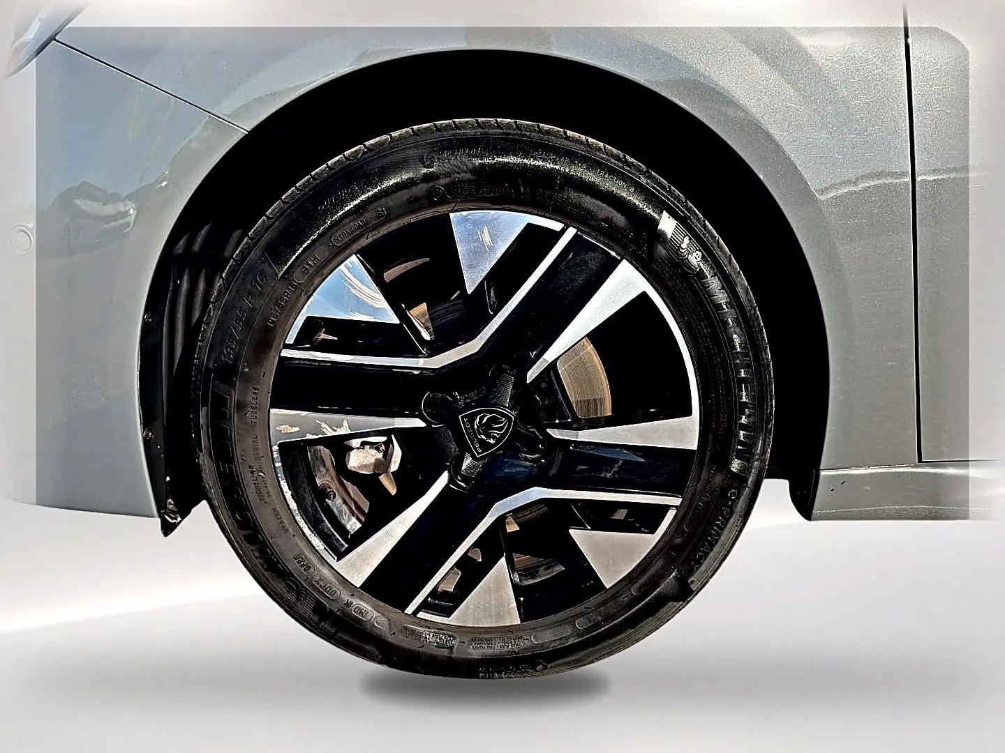 Gros plan sur la jante alu noire et argentée du côté avant gauche d'une Peugeot 208 gris selenium.