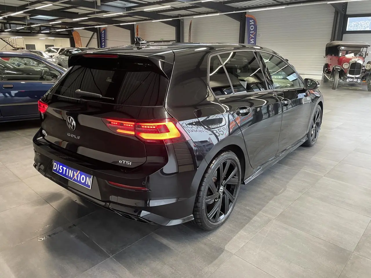 Vue 3/4 arrière droite d'une Volkswagen Golf 1.5 eTSI noire métallisée avec jantes noires 18 pouces en alliage léger.