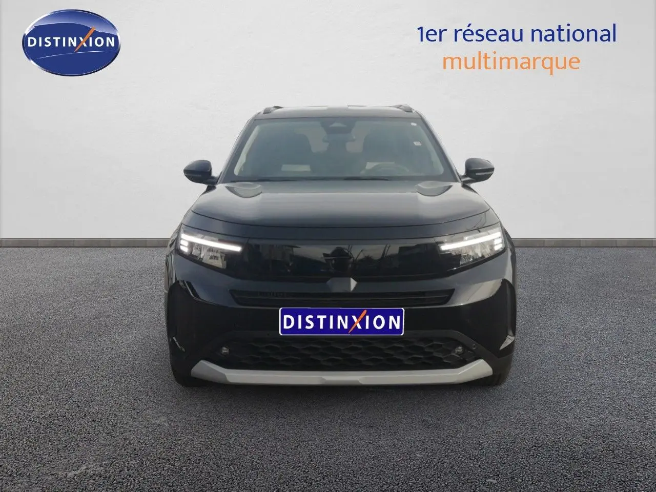 Vue frontale d'un Opel Frontera 1.2 Turbo Hybrid noir Karbon avec calandre moderne et phares LED allumés.
