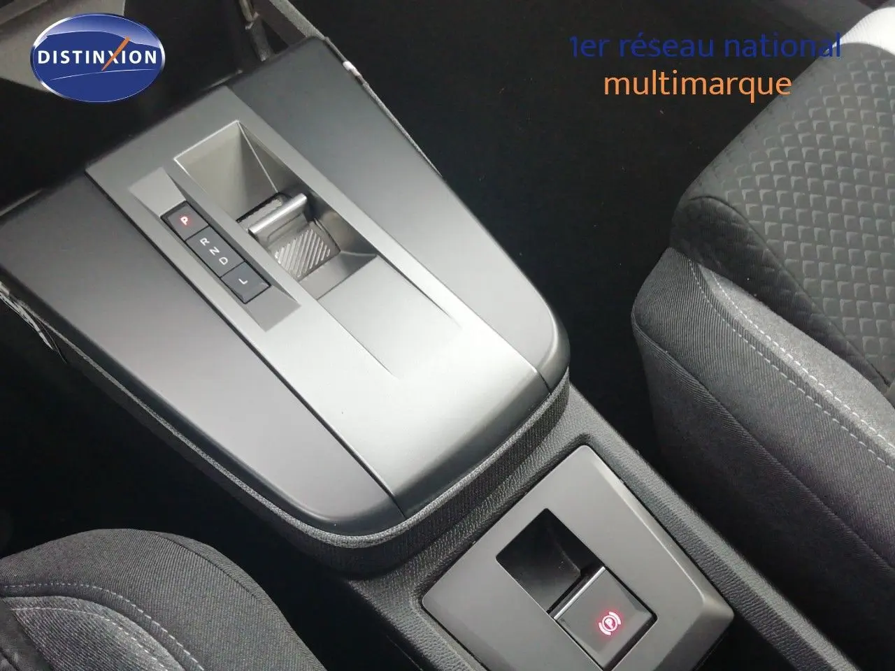Gros plan sur la console centrale avec levier de boîte auto et sièges en tissu gris foncé de l’Opel Frontera noir Karbon.