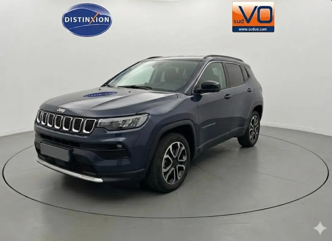 Jeep Compass bleu 3/4 avant droit, jantes alliage 18 pouces, calandre à sept barres chromées, SUV 2024 en studio.
