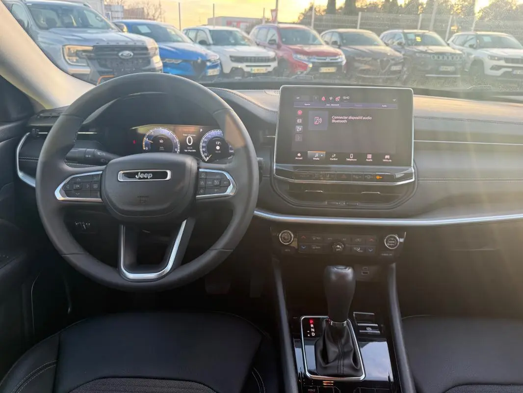 Vue intérieure frontale du tableau de bord du Jeep Compass bleu 2024 avec écran tactile et volant multifonction.