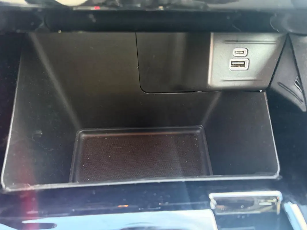 Gros plan sur la console centrale noire du Jeep Compass 2024, avec prises USB visibles dans un compartiment vide.