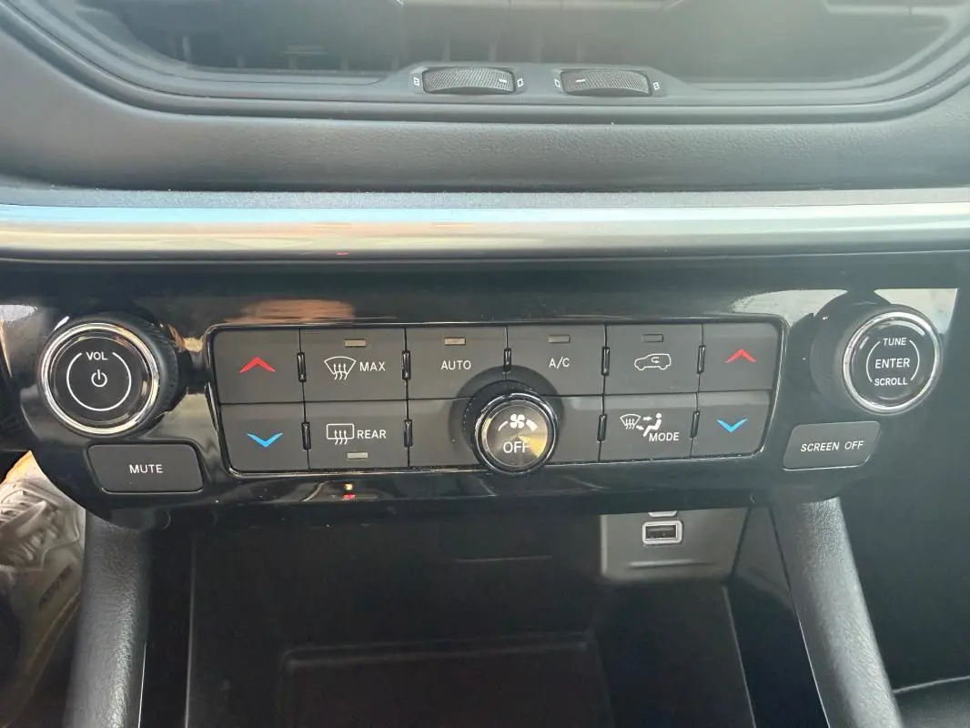 Vue rapprochée de la console centrale noire du Jeep Compass 2024, avec commandes climatisation et audio.