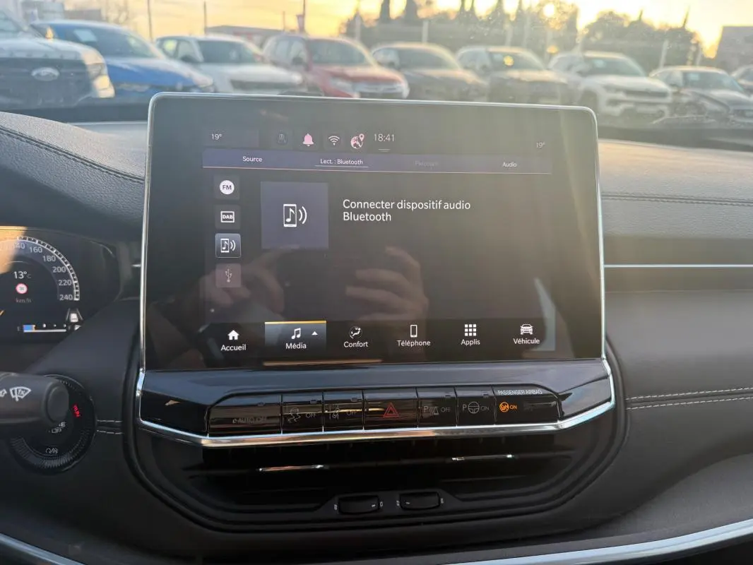 Vue intérieure centrée sur l'écran tactile multimédia du Jeep Compass 2024 avec tableau de bord noir et commandes visibles.