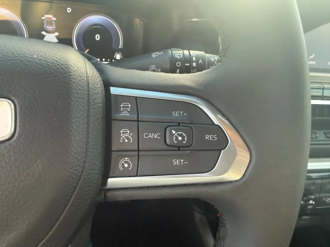 Gros plan sur les commandes du régulateur de vitesse au volant du Jeep Compass bleu 2024, intérieur moderne et fonctionnel.