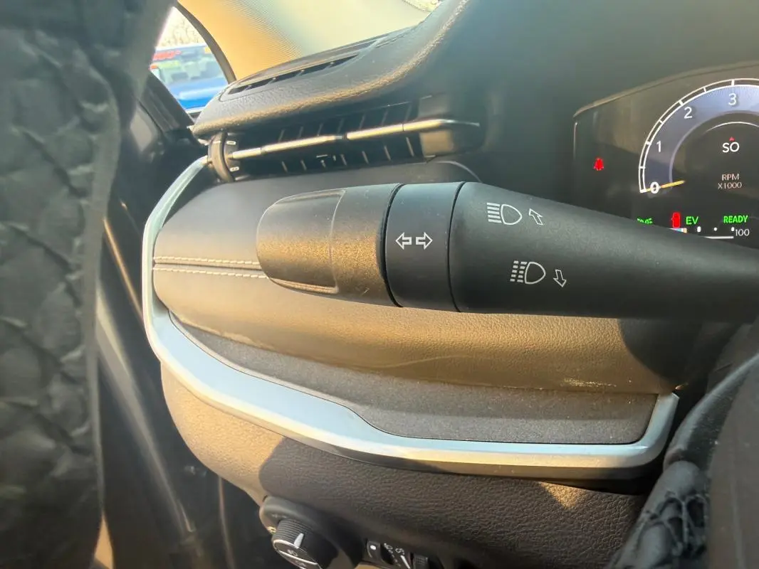 Gros plan sur la commande des clignotants et phares du tableau de bord du Jeep Compass bleu 2024, intérieur noir.