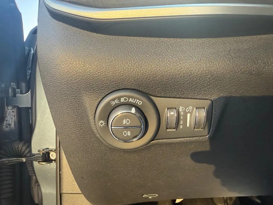 Gros plan sur le panneau de commande des phares et réglages d’éclairage du Jeep Compass 2024, intérieur noir texturé.