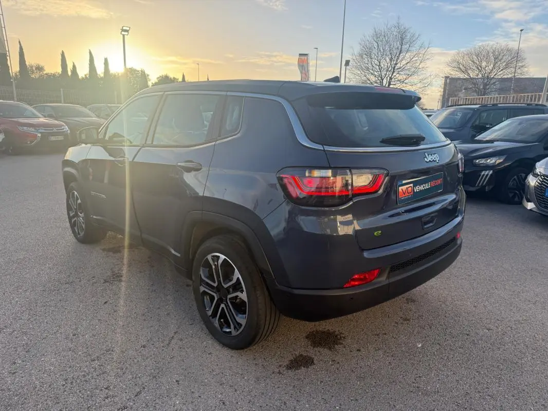 Jeep Compass bleu vue 3/4 arrière droit avec jantes alliage 18 pouces au soleil couchant.