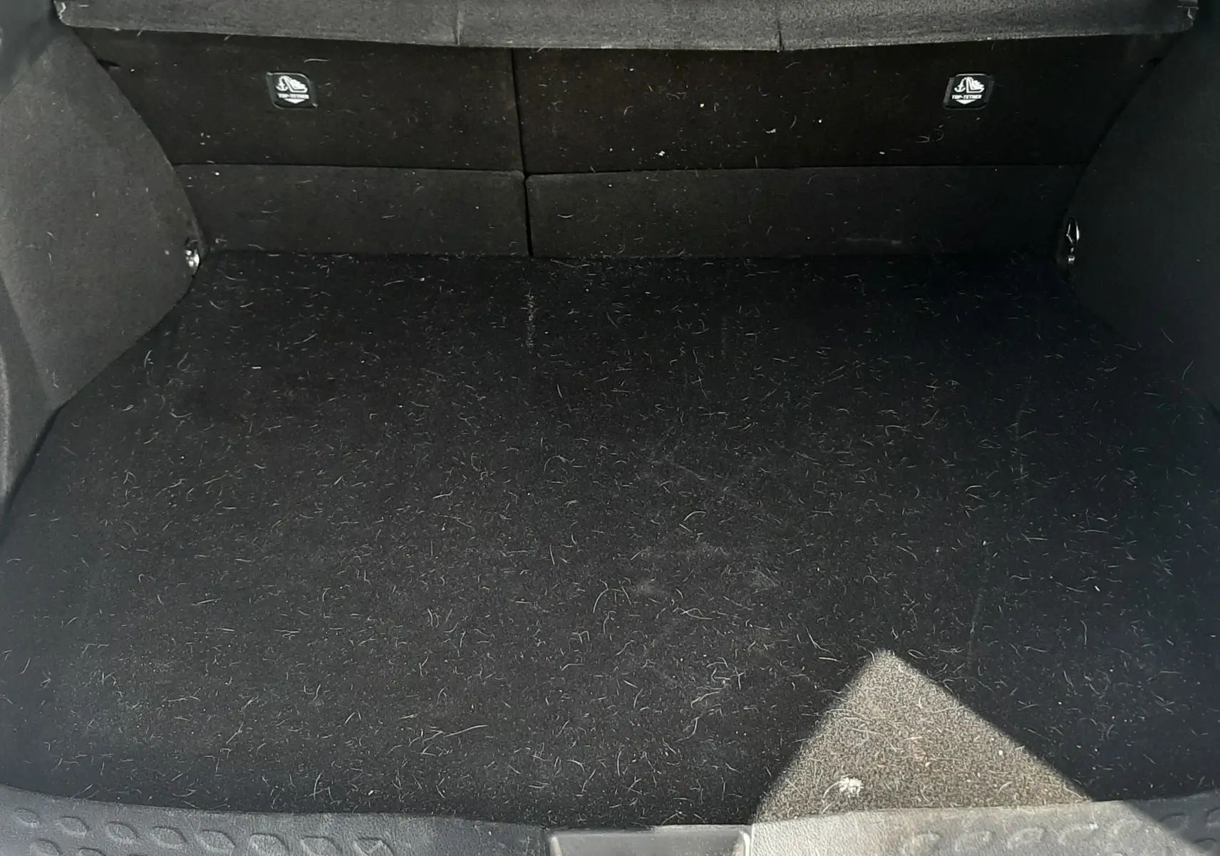 Coffre ouvert vu de face du Toyota C-HR 1.8 Hybrid 122 Design noir, montrant un espace de chargement vide et propre.