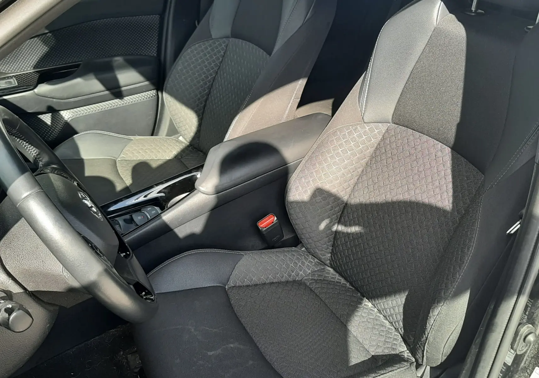 Vue intérieure côté conducteur du Toyota C-HR 1.8 Hybrid 122 Design 2023 avec sièges tissu noir et console centrale.