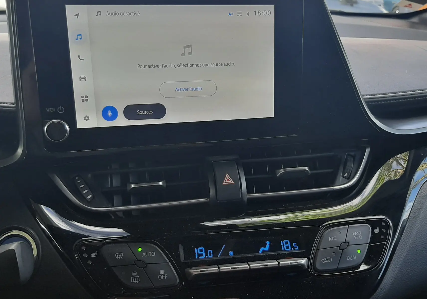 Vue rapprochée de la console centrale noire du Toyota C-HR 1.8 Hybrid 2023 avec écran tactile et commandes climatisation digitales.