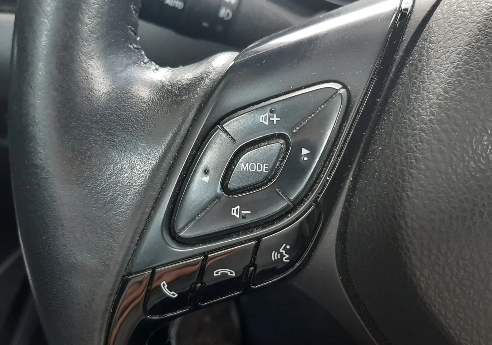Gros plan sur les commandes multifonctions noires du volant côté gauche du Toyota C-HR 1.8 Hybrid 2023.