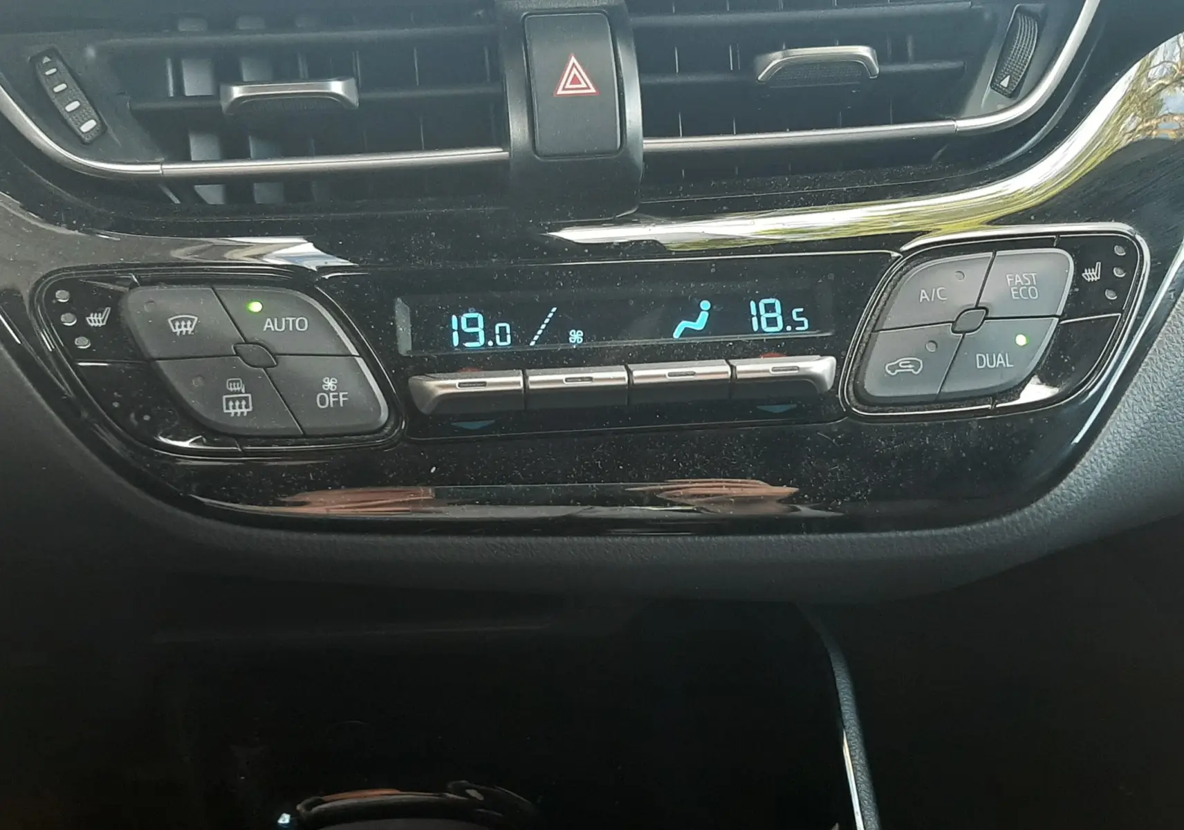 Vue rapprochée du tableau de bord noir du Toyota C-HR 1.8 Hybrid 2023, affichant la climatisation automatique dual zone.