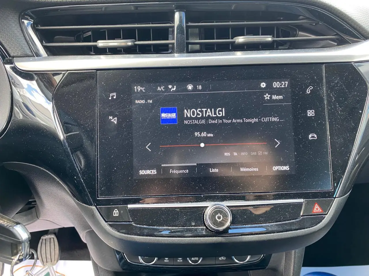Gros plan sur l'écran tactile central noir de l'Opel Corsa 1.2i Turbo 2021, affichant la radio FM Nostalgie.