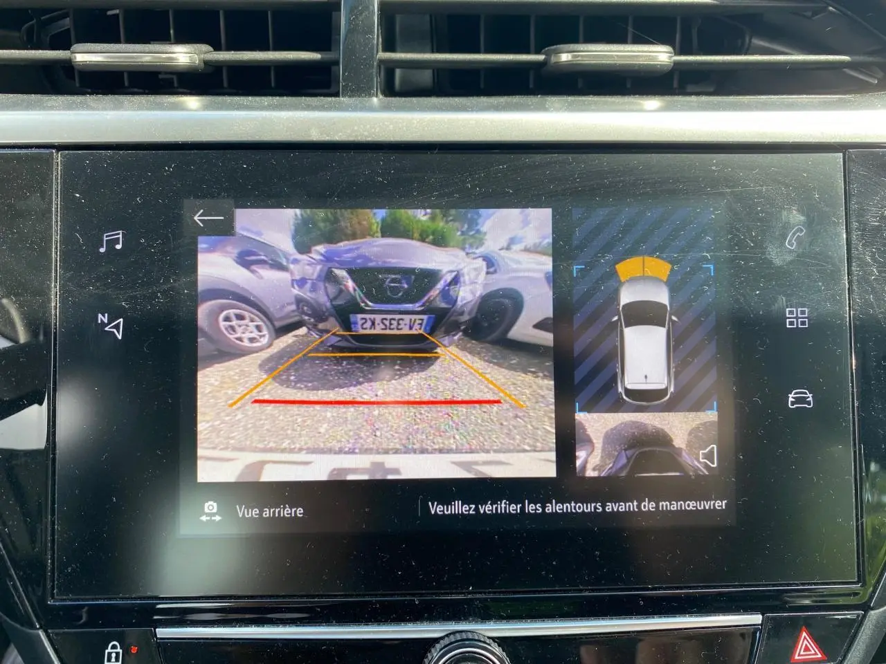 Écran tactile intérieur montrant la caméra de recul avec vue arrière et aide au stationnement active.