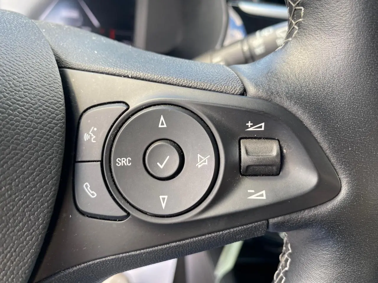 Gros plan sur les commandes gauche du volant en cuir noir de l’Opel Corsa 1.2i Turbo 2021, boutons multifonctions.