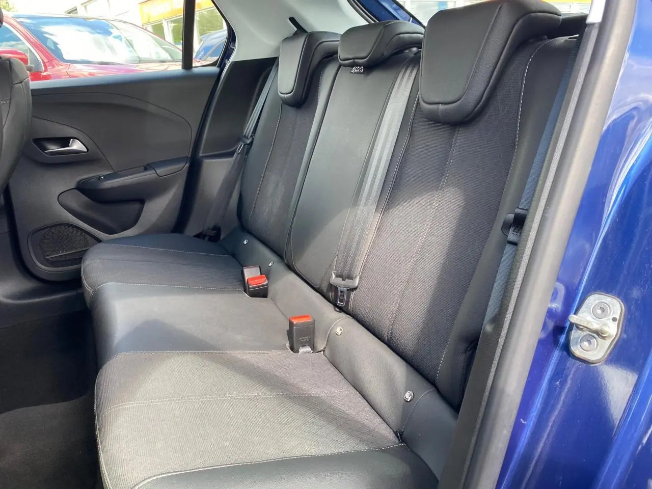 Vue intérieure côté droit des sièges arrière noirs d'une Opel Corsa bleu nautique 2021 avec ceinture de sécurité visible.