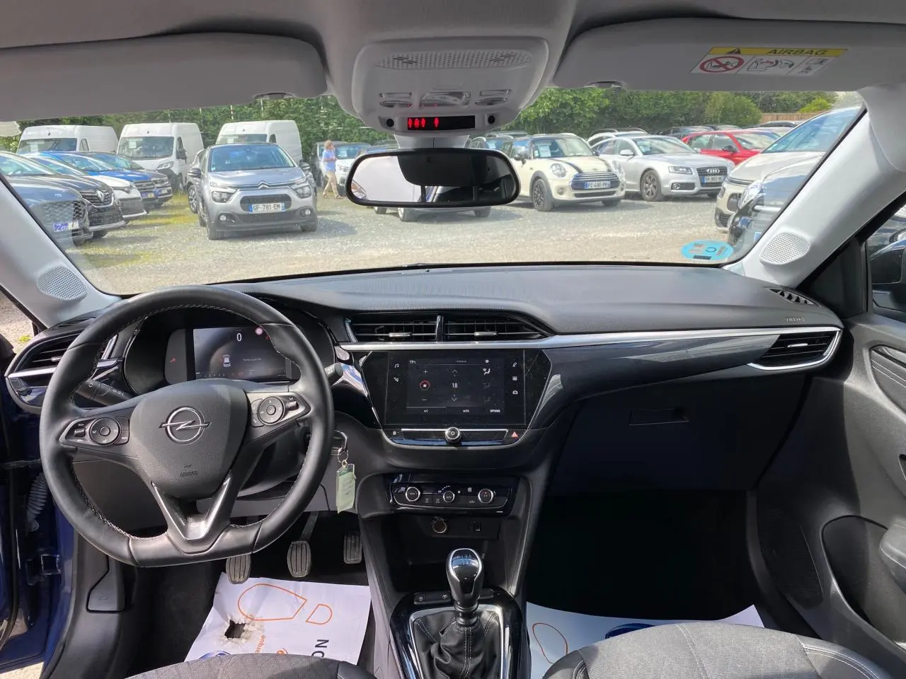 Vue intérieure avant de l’Opel Corsa bleu nautique, montrant le volant cuir multifonction et l’écran digital central.
